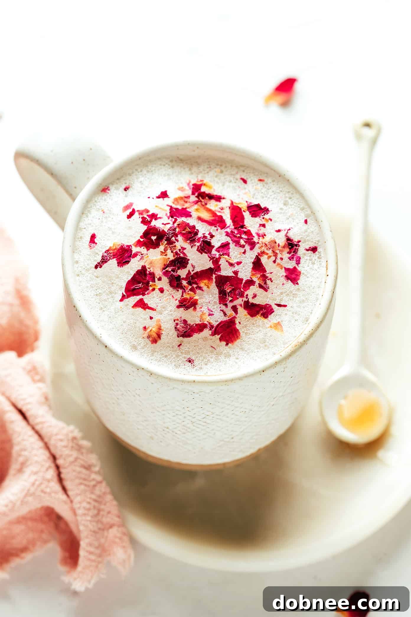 Velvet Rose Latte 5 A refreshing iced vanilla rose latte in a tall glass, adorned with vibrant dried rose petals.