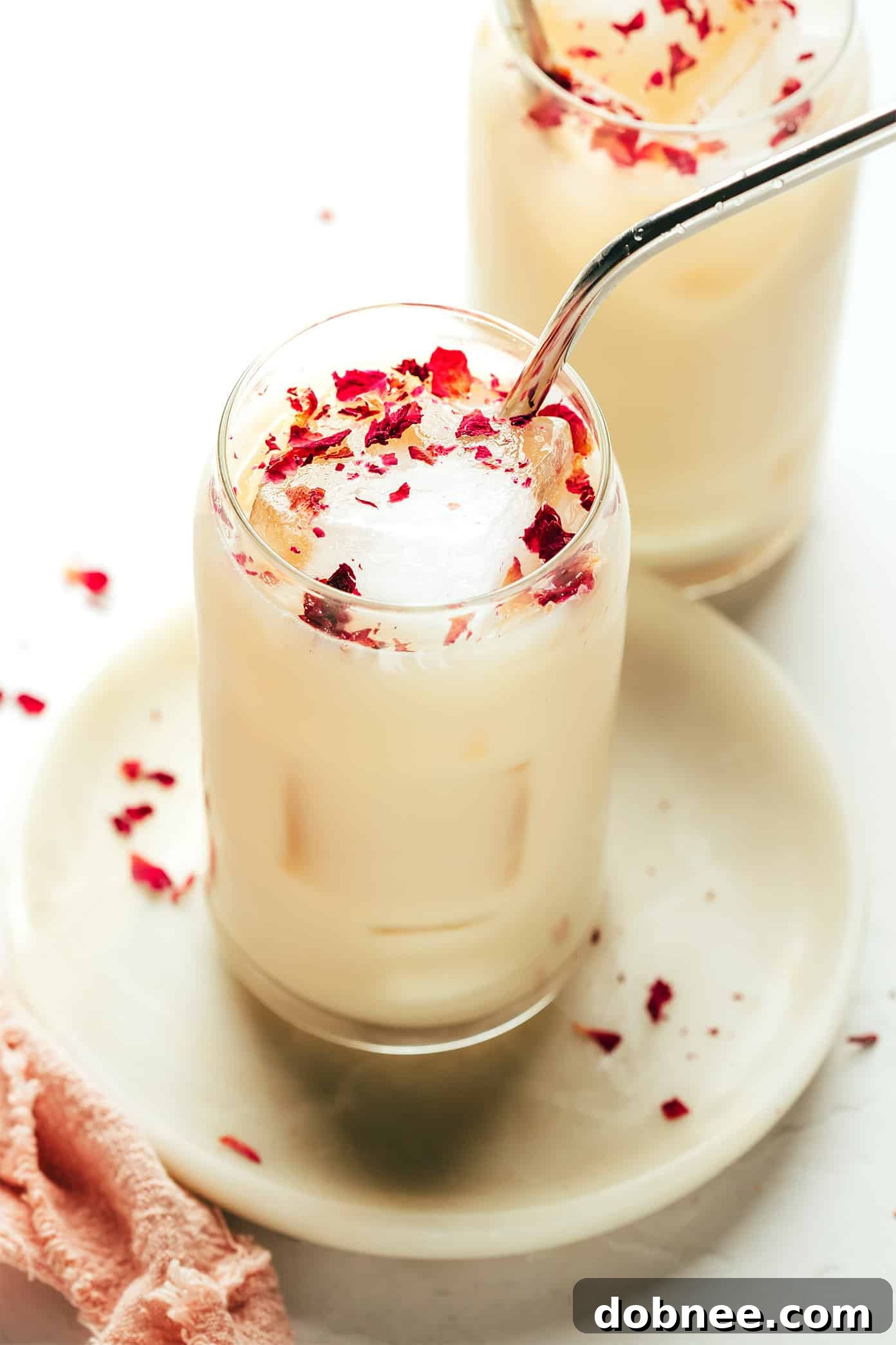 Velvet Rose Latte 6 Overhead view of two rose lattes, one hot and one iced, both garnished with rose petals, inviting a cozy experience.