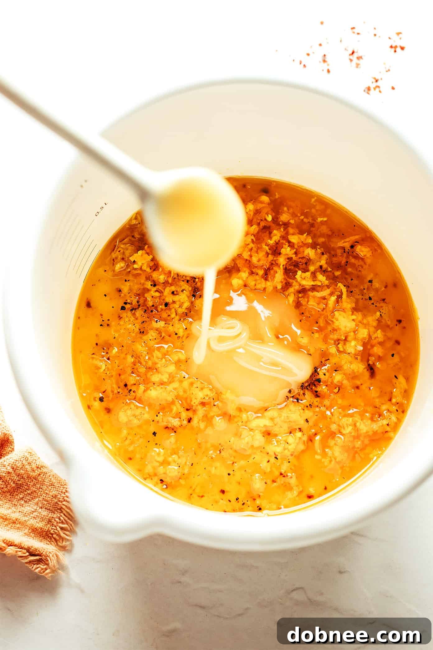 Ginger Hot Honey Vinaigrette in a small bowl, garnished with fresh ginger and chili flakes