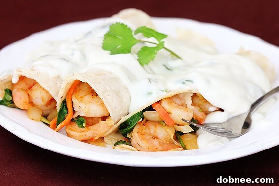 Rich verde shrimp enchiladas drenched in a creamy jalapeno sauce, garnished with fresh cilantro.
