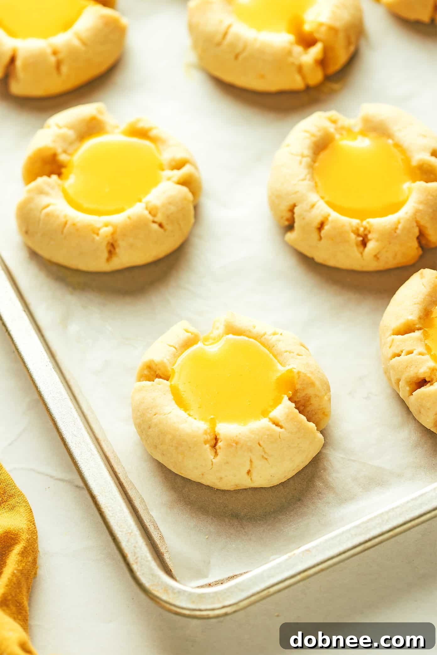 Freshly baked lemon thumbprint cookies arranged on a baking sheet, ready for filling