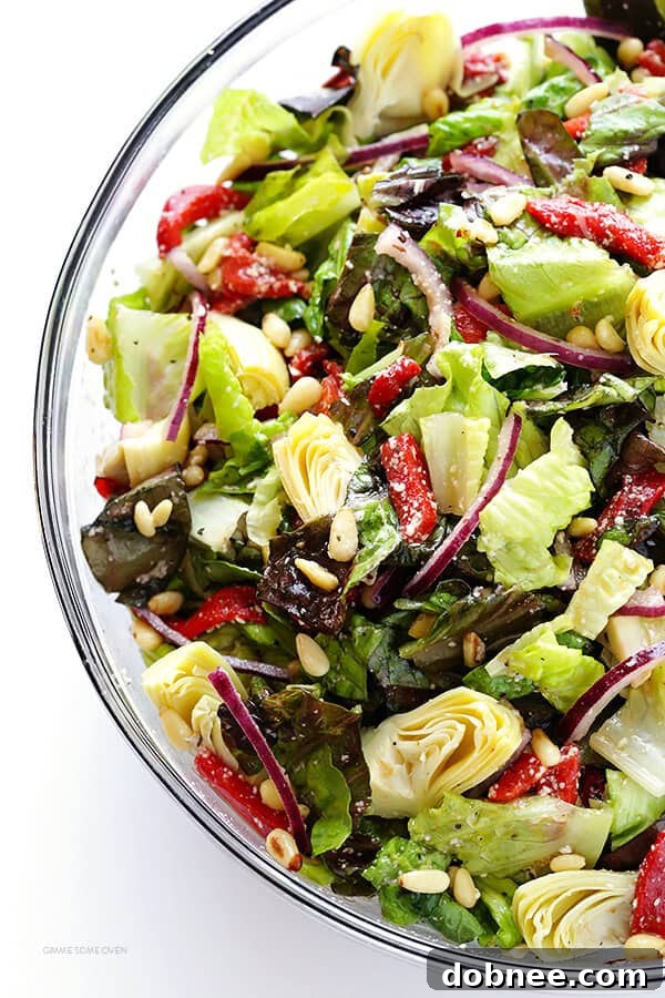 Our Family's Favorite Salad is made with lots of artichoke hearts, roasted red peppers, toasted pine nuts, and a zesty Parmesan vinaigrette. SO delicious, and always a crowd pleaser! | gimmesomeoven.com