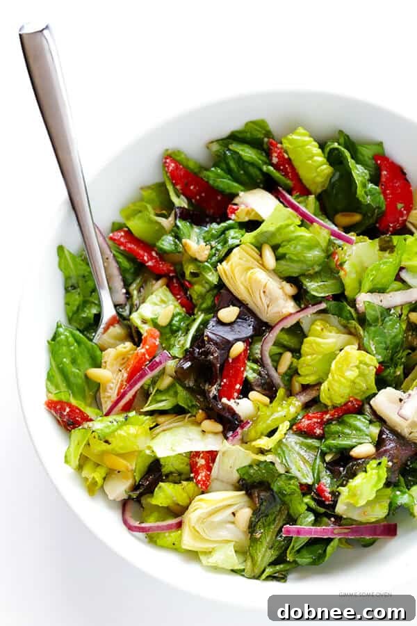 Our Family's Favorite Salad is made with lots of artichoke hearts, roasted red peppers, toasted pine nuts, and a zesty Parmesan vinaigrette. SO delicious, and always a crowd pleaser! | gimmesomeoven.com