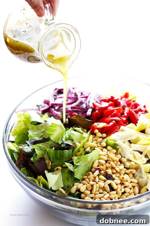 Our Family's Favorite Salad is made with lots of artichoke hearts, roasted red peppers, toasted pine nuts, and a zesty Parmesan vinaigrette. SO delicious, and always a crowd pleaser! | gimmesomeoven.com