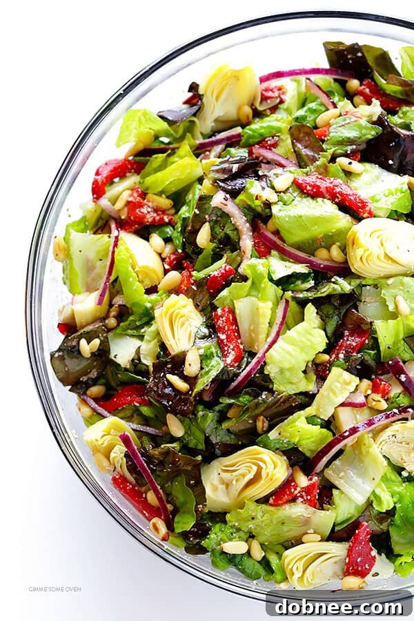 Our Family's Favorite Salad is made with lots of artichoke hearts, roasted red peppers, toasted pine nuts, and a zesty Parmesan vinaigrette. SO delicious, and always a crowd pleaser! | gimmesomeoven.com