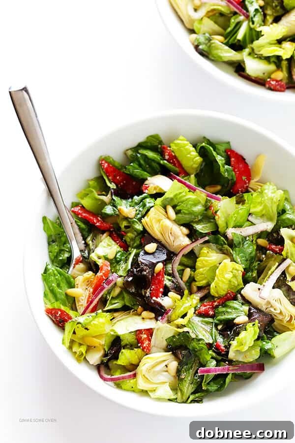 Our Family's Favorite Salad is made with lots of artichoke hearts, roasted red peppers, toasted pine nuts, and a zesty Parmesan vinaigrette. SO delicious, and always a crowd pleaser! | gimmesomeoven.com