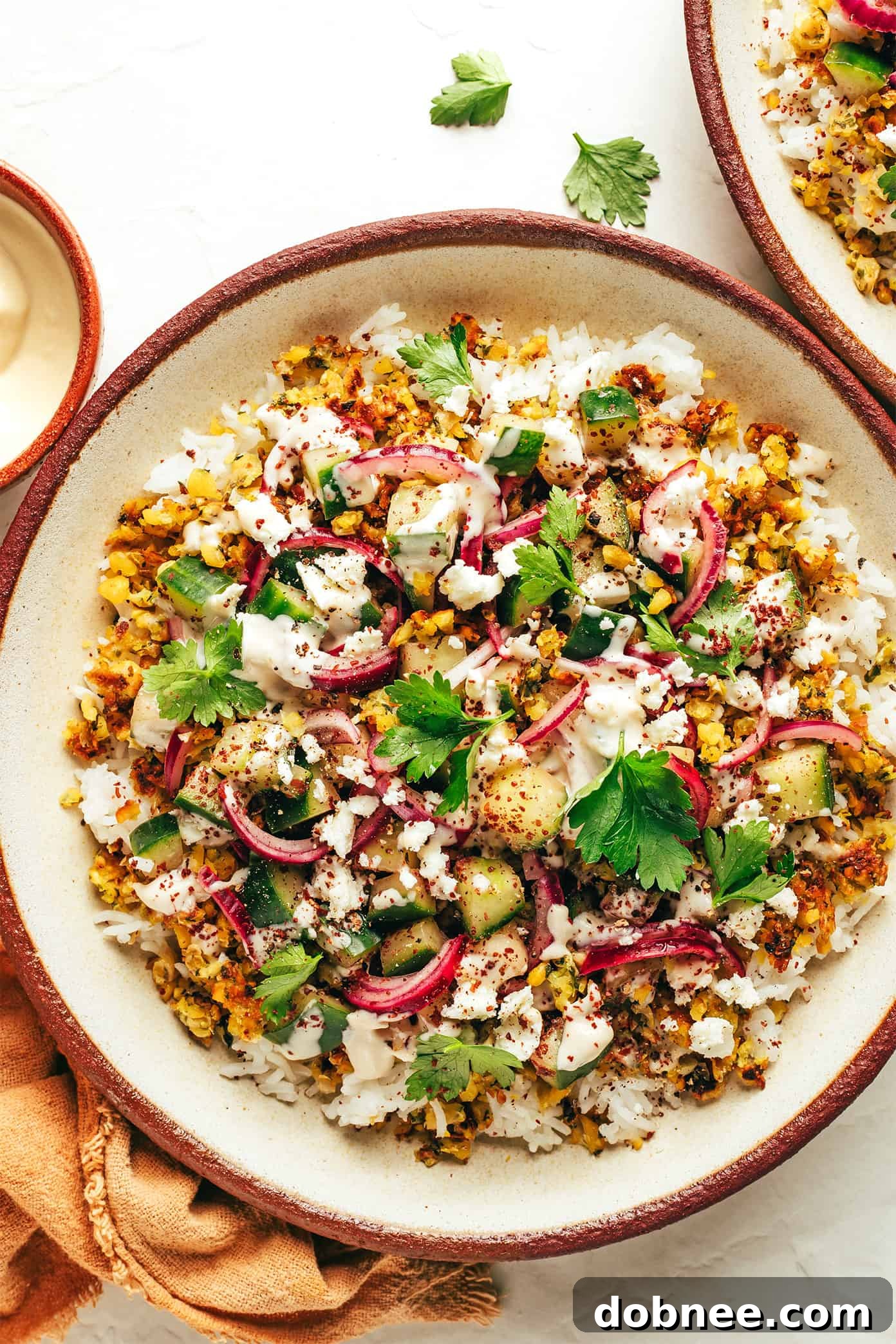 A vibrant Crumbled Falafel Bowl garnished with fresh lemon and herbs.