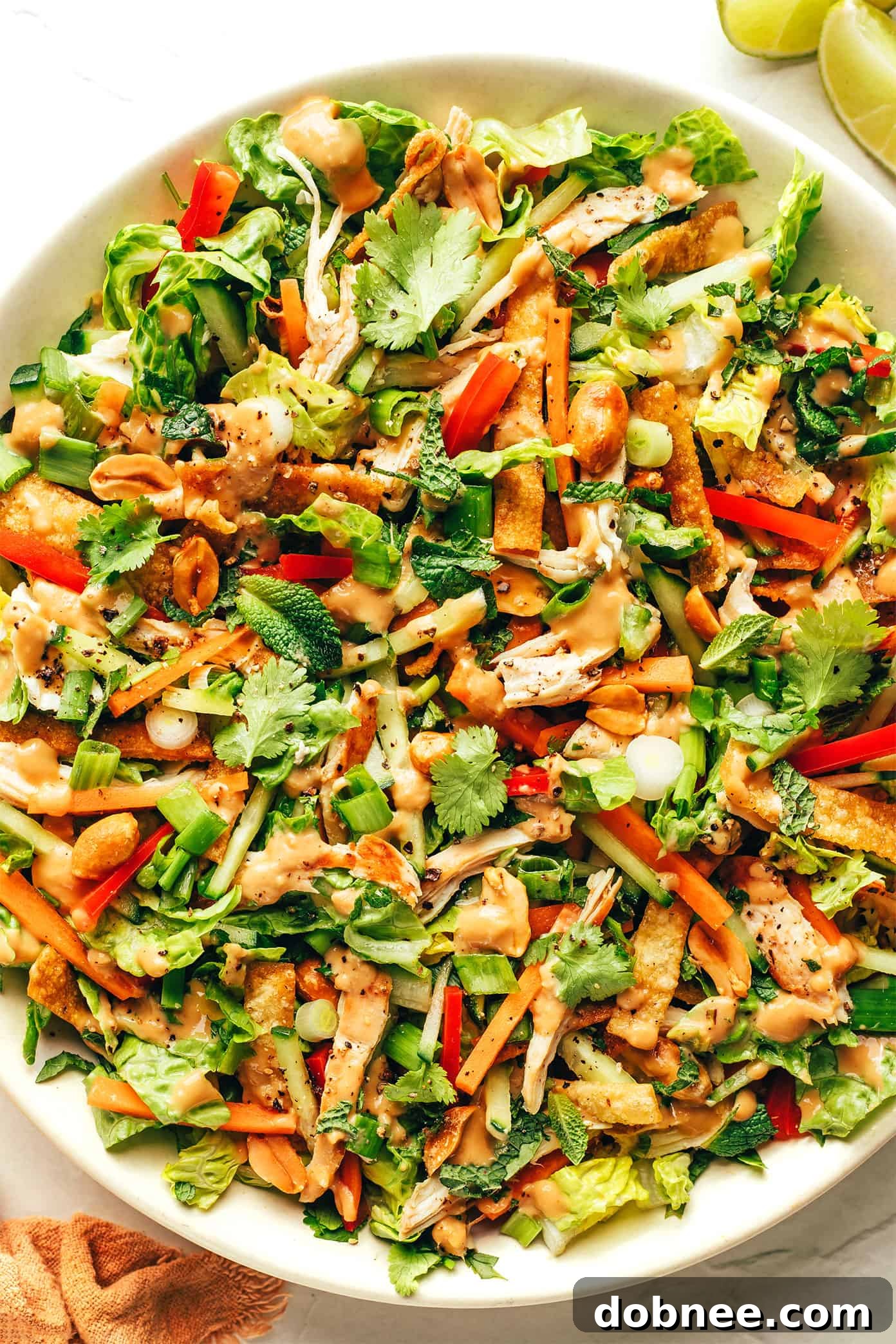 The finished Thai Crunch Salad, beautifully tossed and generously drizzled with the creamy peanut dressing, presented in a bowl ready to be served.