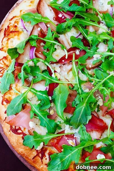 Close-up of baked Pear, Prosciutto, Arugula & Gorgonzola Pizza with fresh arugula