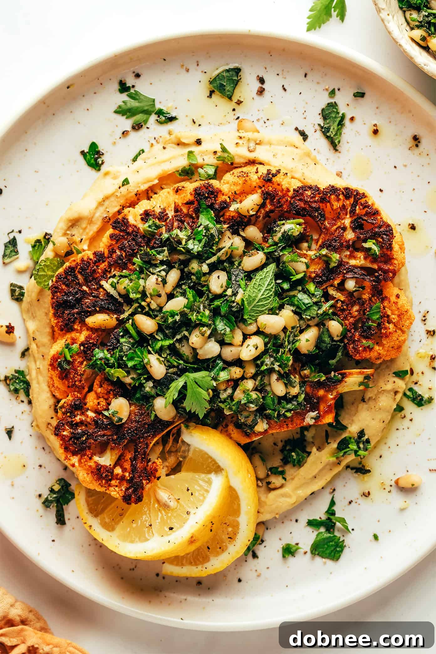 Delicious Cauliflower Steaks served over hummus with a fresh gremolata topping