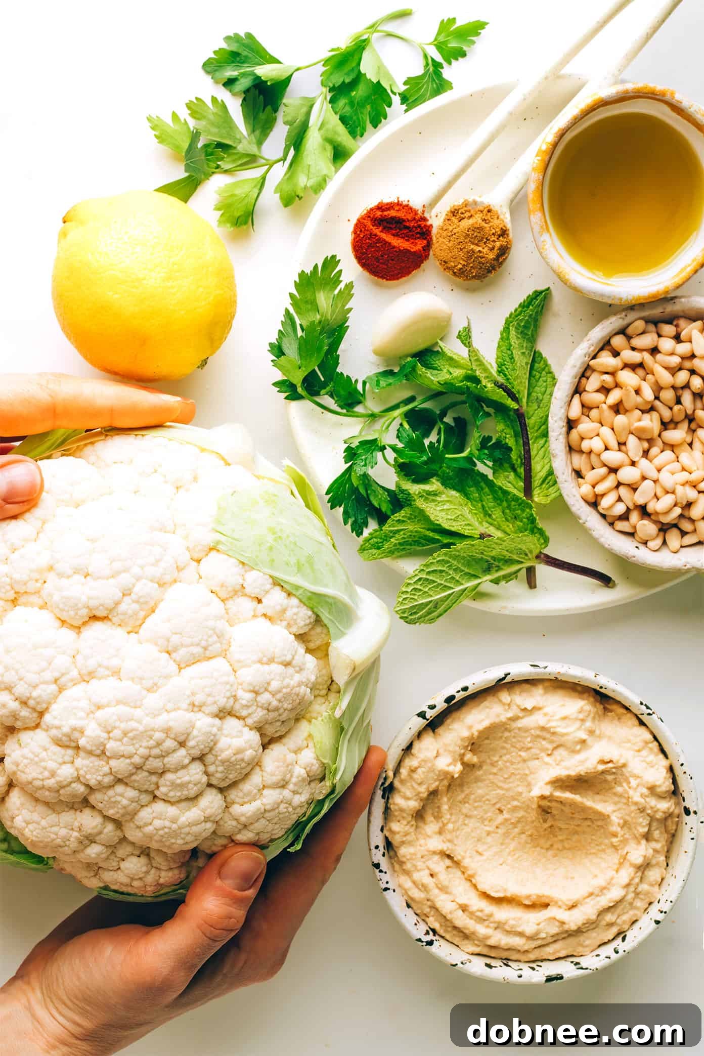 Two plates of Cauliflower Steaks with Hummus and Gremolata, garnished with lemon