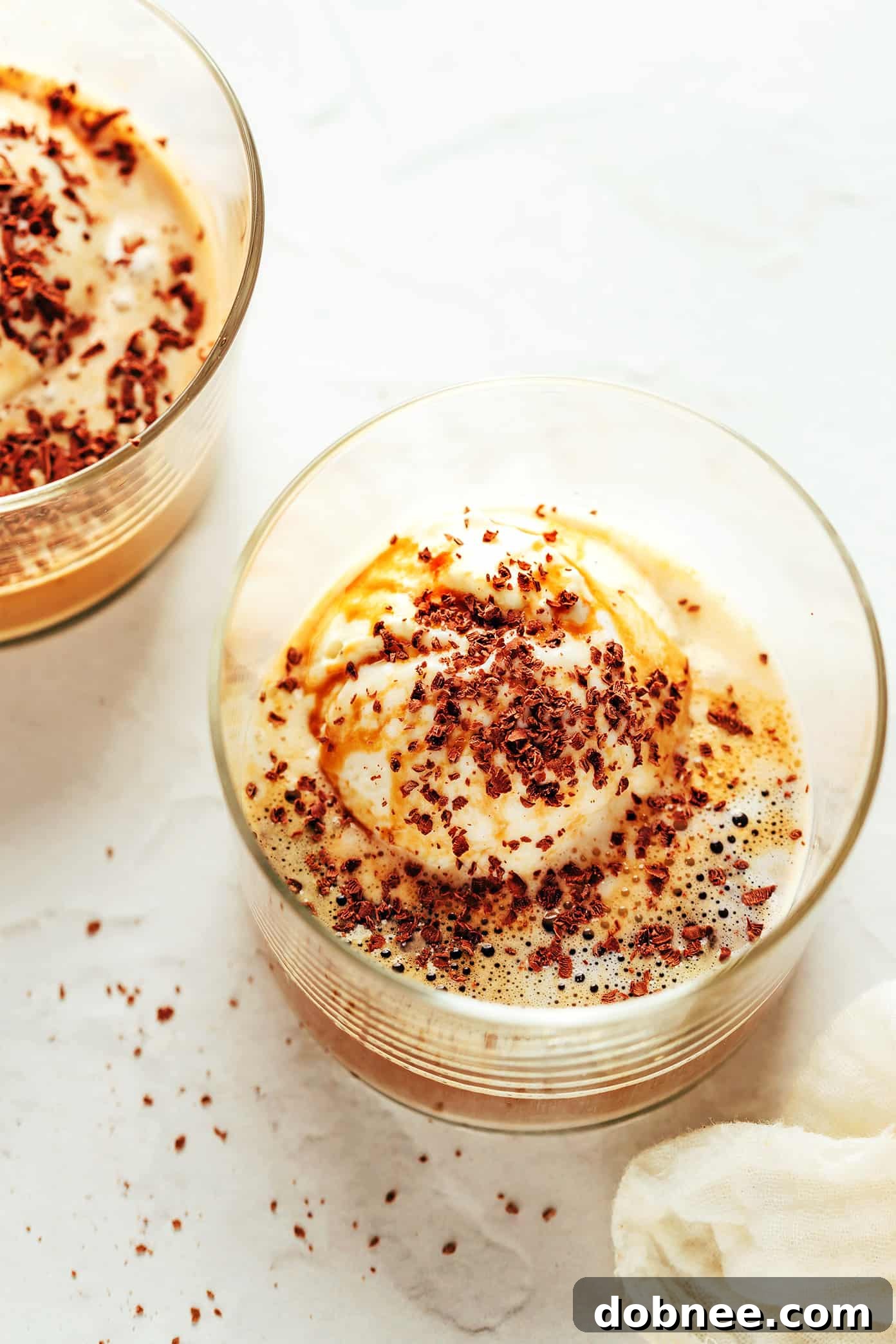 A beautifully presented affogato with a scoop of vanilla ice cream, espresso poured over it, and chocolate shavings on top, in an elegant glass.