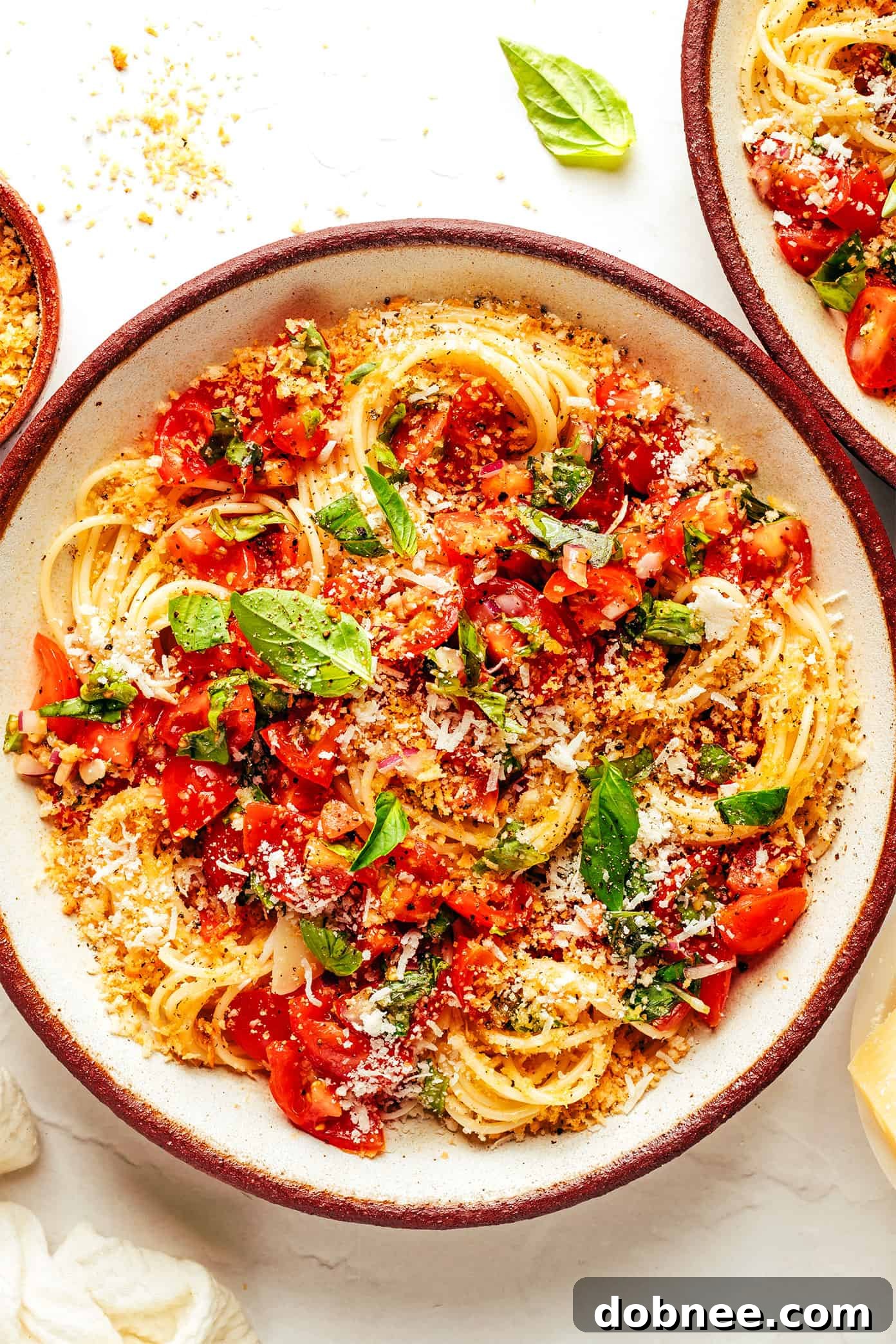 A beautifully plated dish of Fresh Bruschetta Pasta, showcasing vibrant red cherry tomatoes, green basil leaves, and golden breadcrumbs mixed with spaghetti.