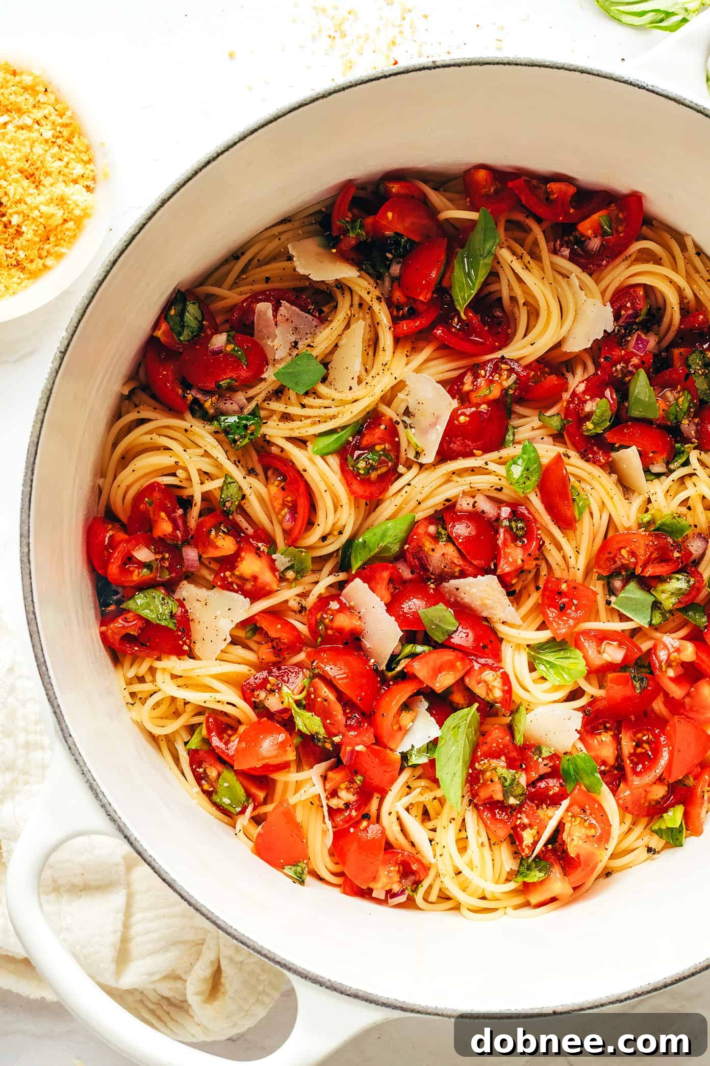 A large serving bowl filled with Bruschetta Pasta, topped with fresh basil and breadcrumbs, ready to be served.