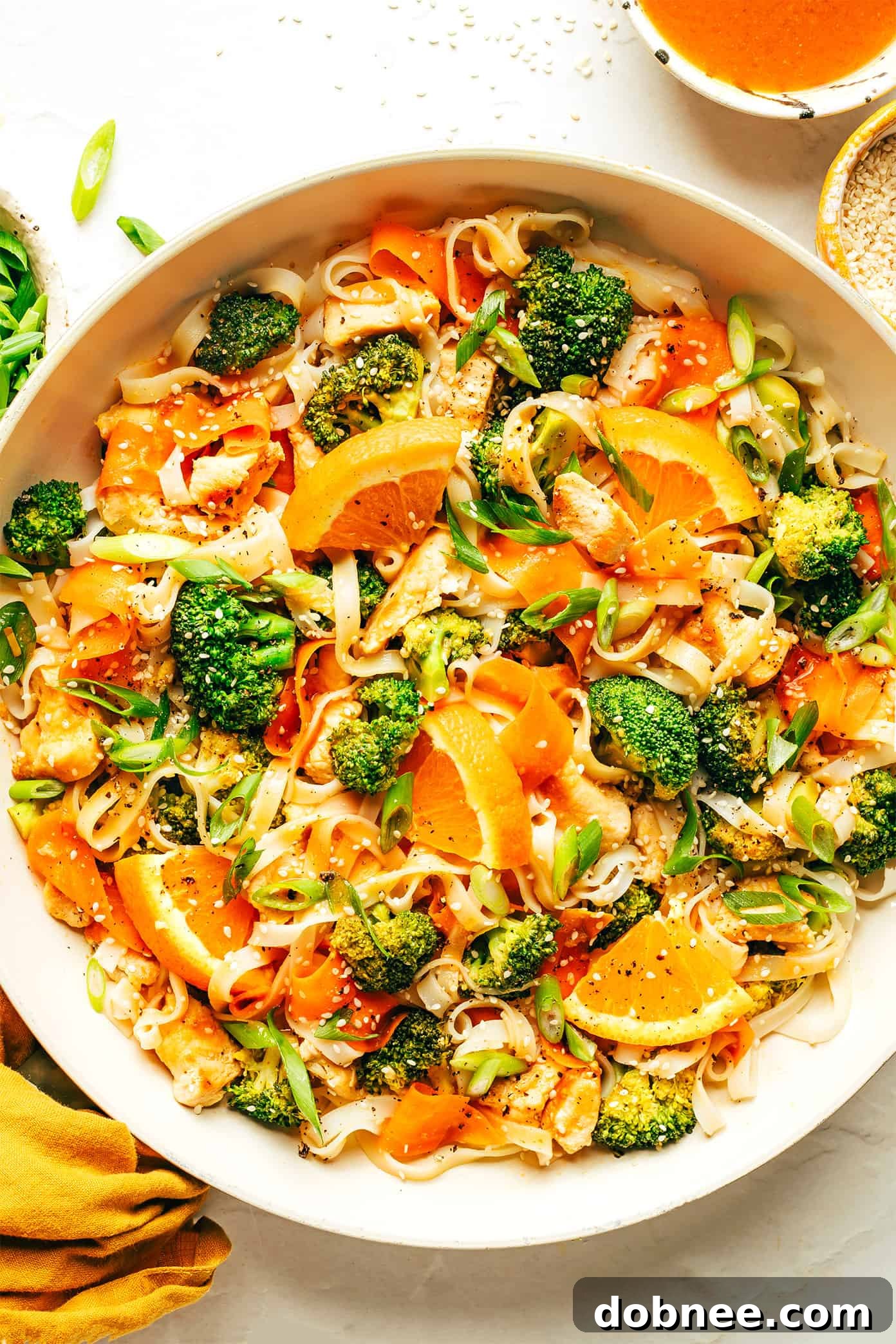 A serving of Orange Miso Noodle Stir-Fry garnished with fresh scallions and sesame seeds.