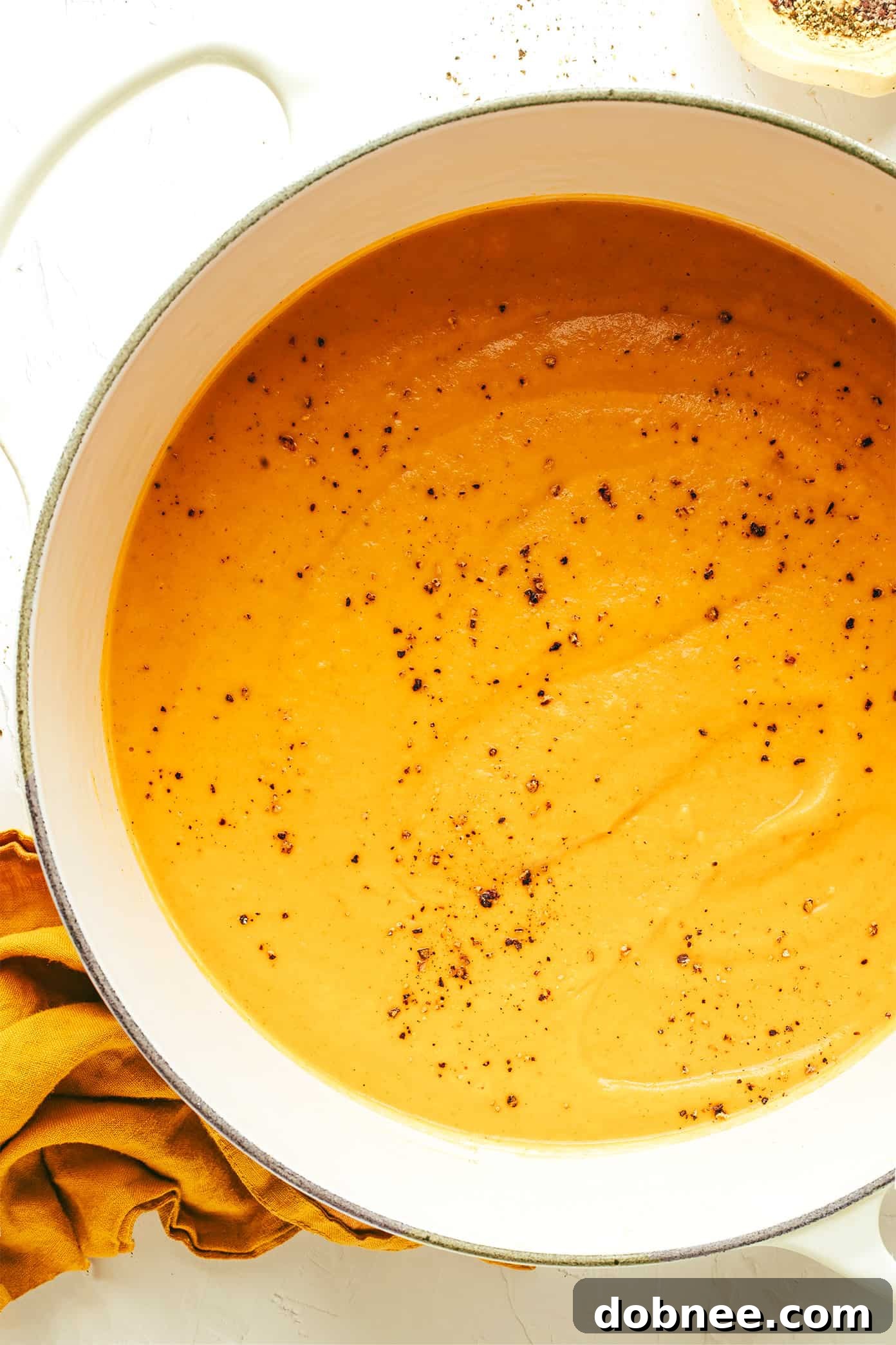 Velvety Vegetable Medley 5 A beautifully presented bowl of creamy roasted vegetable soup, garnished with green herbs and a swirl of cream, on a wooden table.