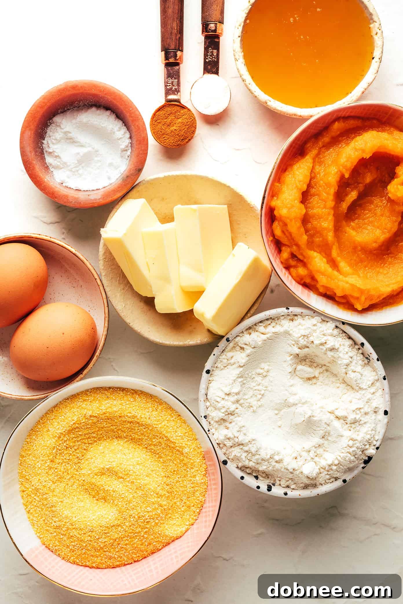 Close-up shot of pumpkin cornbread batter being mixed in a bowl, highlighting the creamy, slightly orange texture before baking.