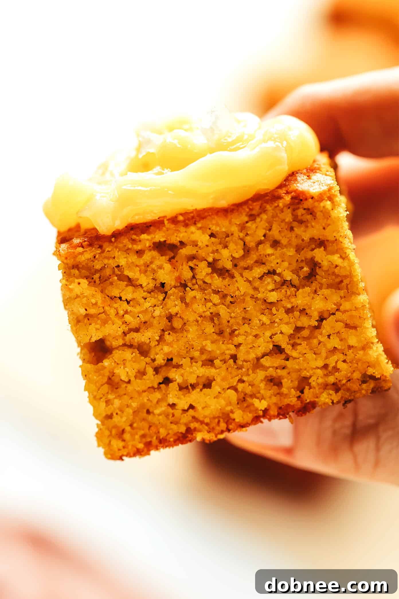 A full view of the delicious pumpkin cornbread, perfectly sliced into squares, ready to be served, with a hint of honey butter nearby on a serving platter.