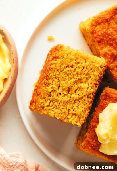 A final, enticing overhead image of the golden-brown pumpkin cornbread, sliced and ready for serving, resting on a cooling rack with a warm, inviting glow, hinting at its deliciousness.