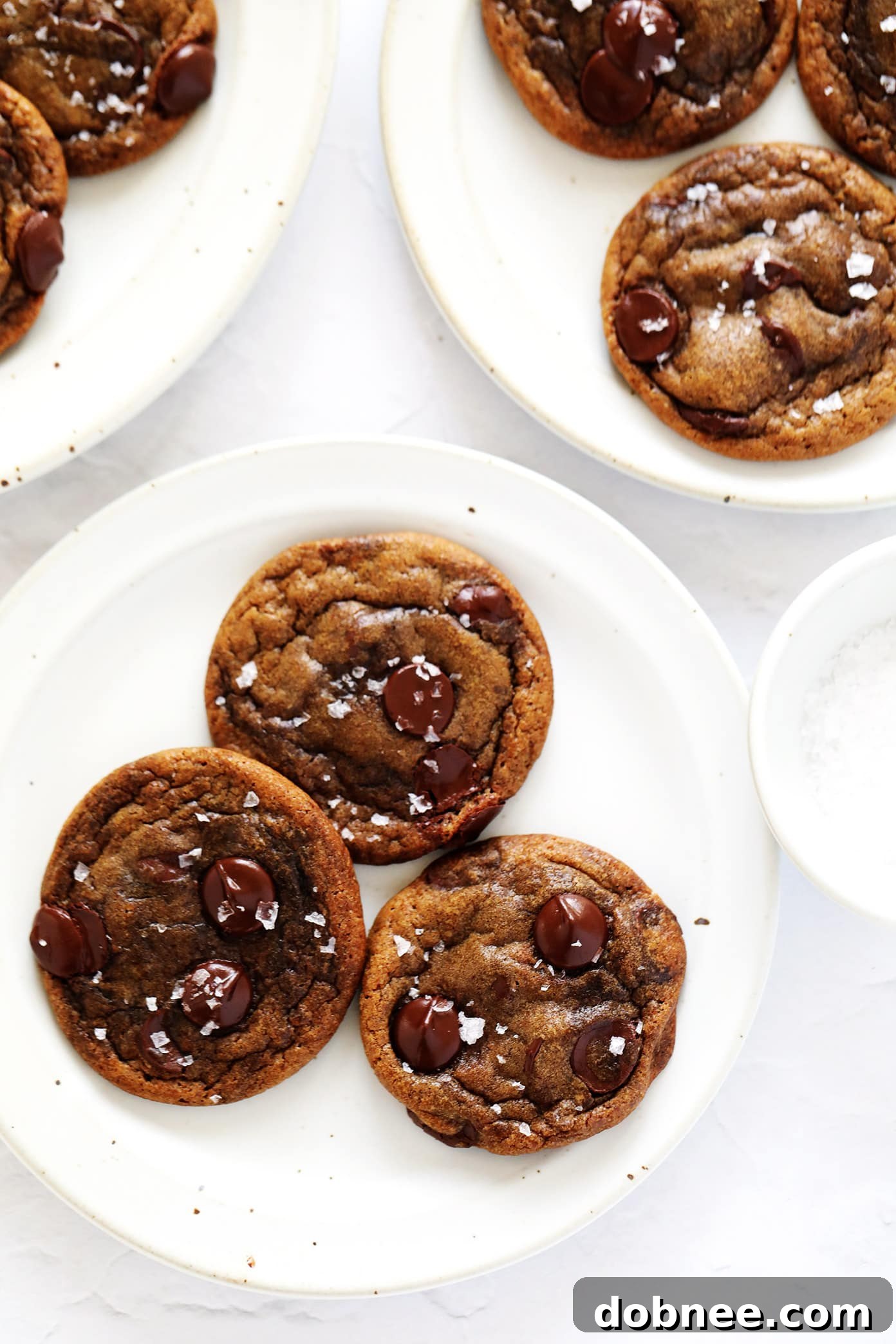 A stack of freshly baked espresso chocolate chip cookies, with visible chocolate chips and a sprinkle of sea salt.