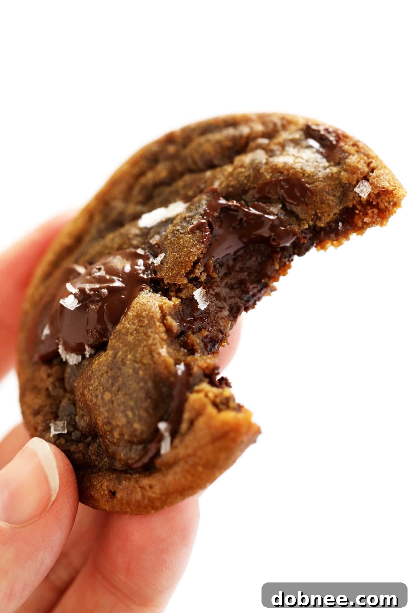 A large pile of baked espresso chocolate chip cookies on a white plate, glistening with melted chocolate.