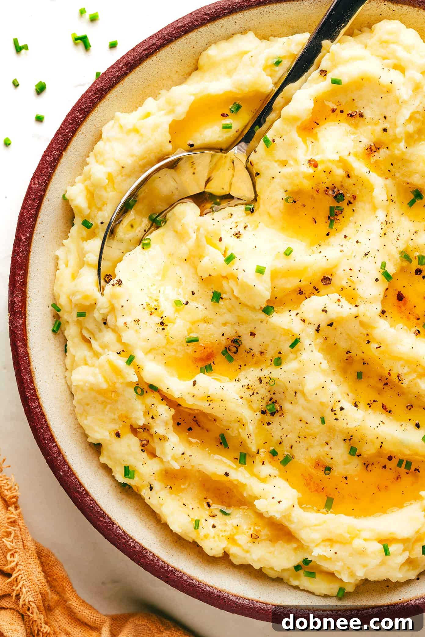 A bowl of creamy brown butter mashed potatoes, garnished with fresh chives, ready to be served.