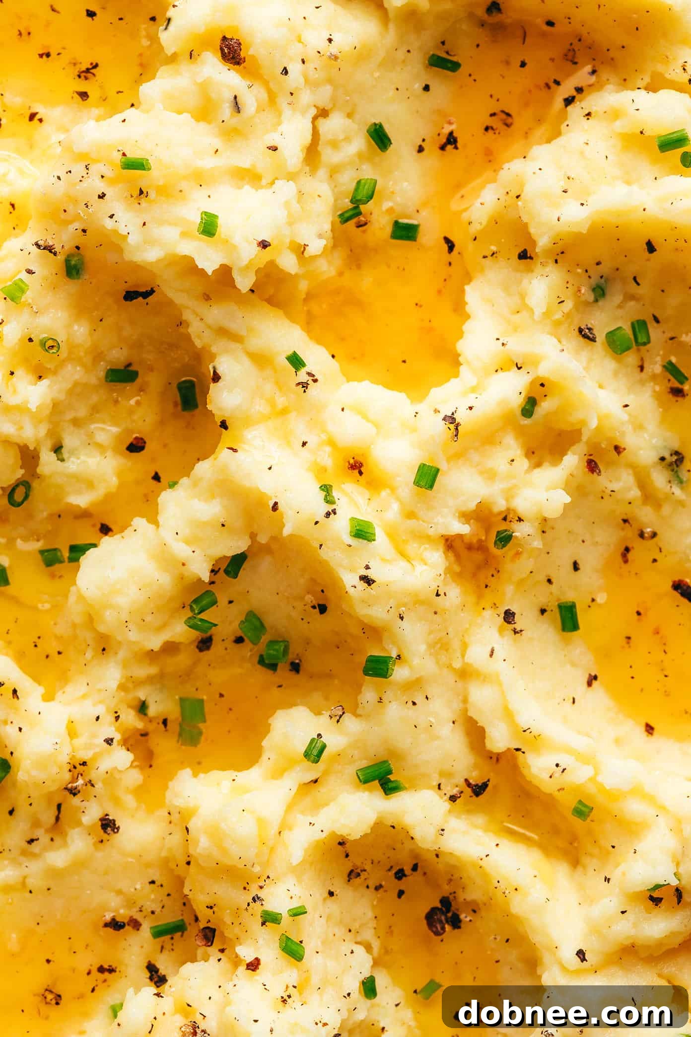 A generous serving of brown butter mashed potatoes in a white bowl, with steam gently rising, inviting you to indulge.