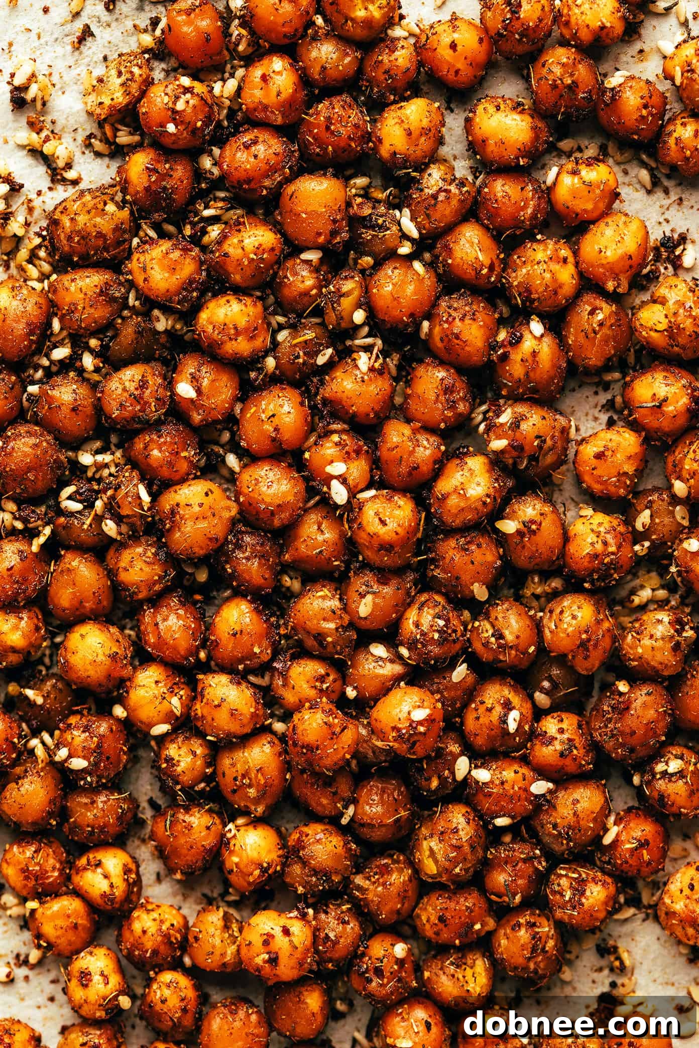 A bowl of creamy roasted carrot soup garnished with a generous amount of crispy za'atar chickpeas.