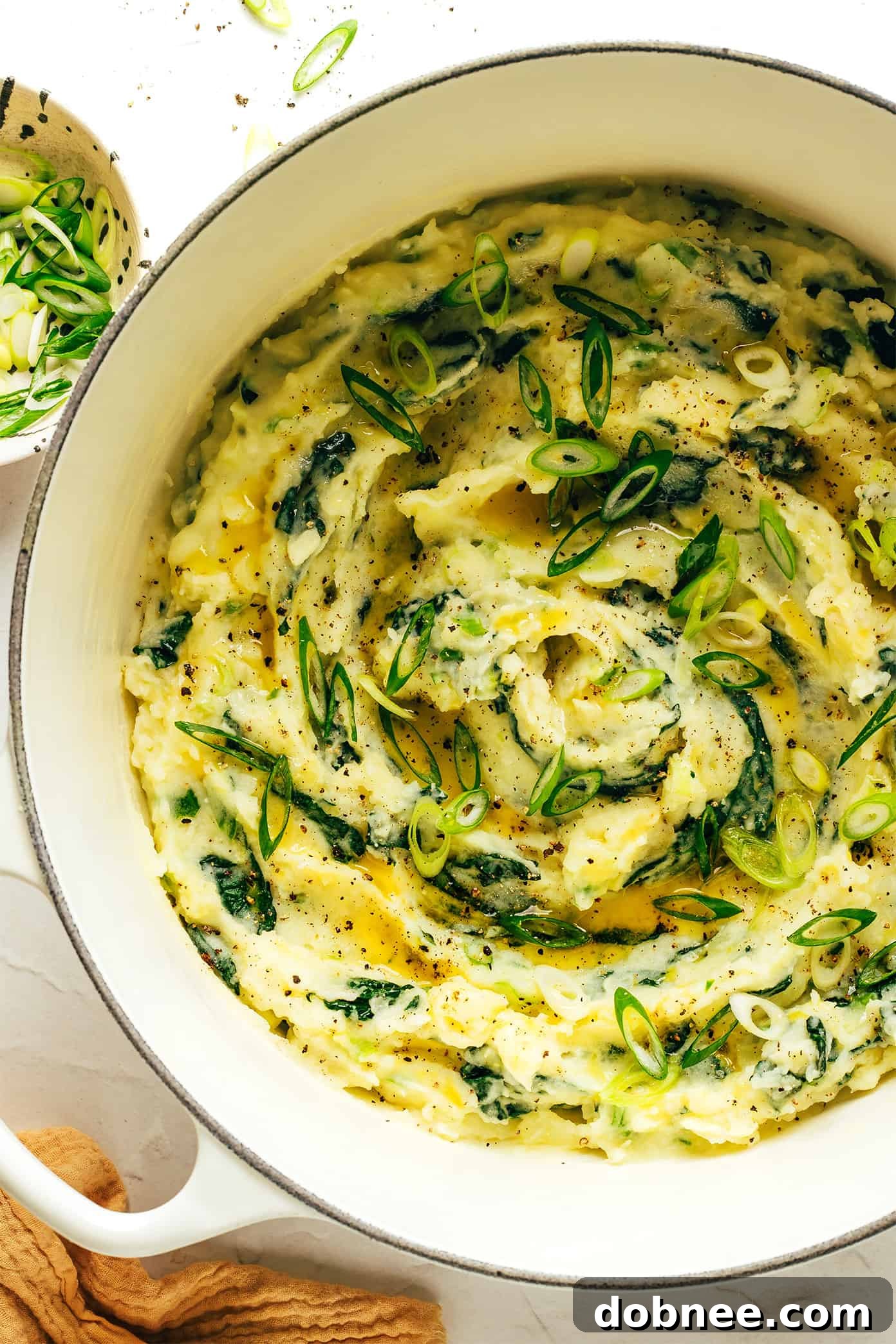 A large serving spoon scooping a portion of Colcannon from a white bowl, showing its rich texture.