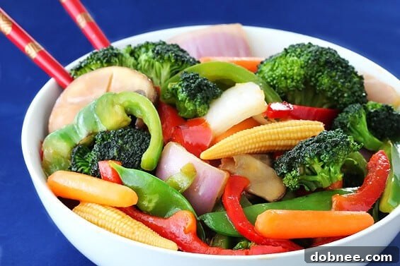 Vibrant and colorful Ginger Vegetable Stir Fry in a white bowl, garnished with toasted sesame seeds, ready to be served.