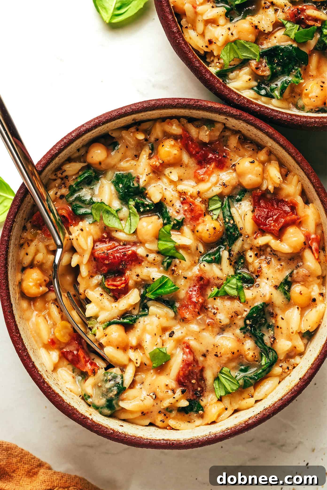 Creamy Marry Me Chickpeas and Orzo in a pan, garnished with fresh basil