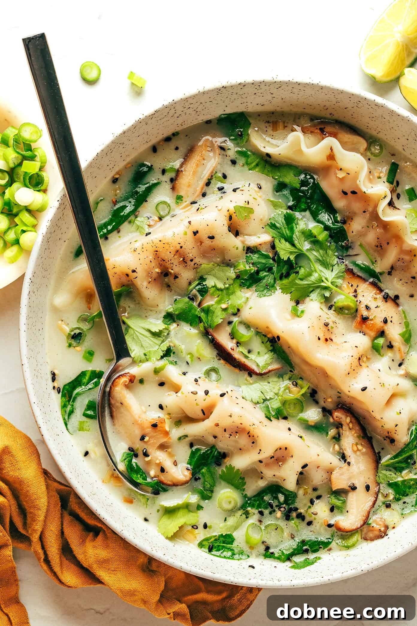 Delicious Ginger Coconut Potsticker Soup in a bowl, garnished with fresh herbs