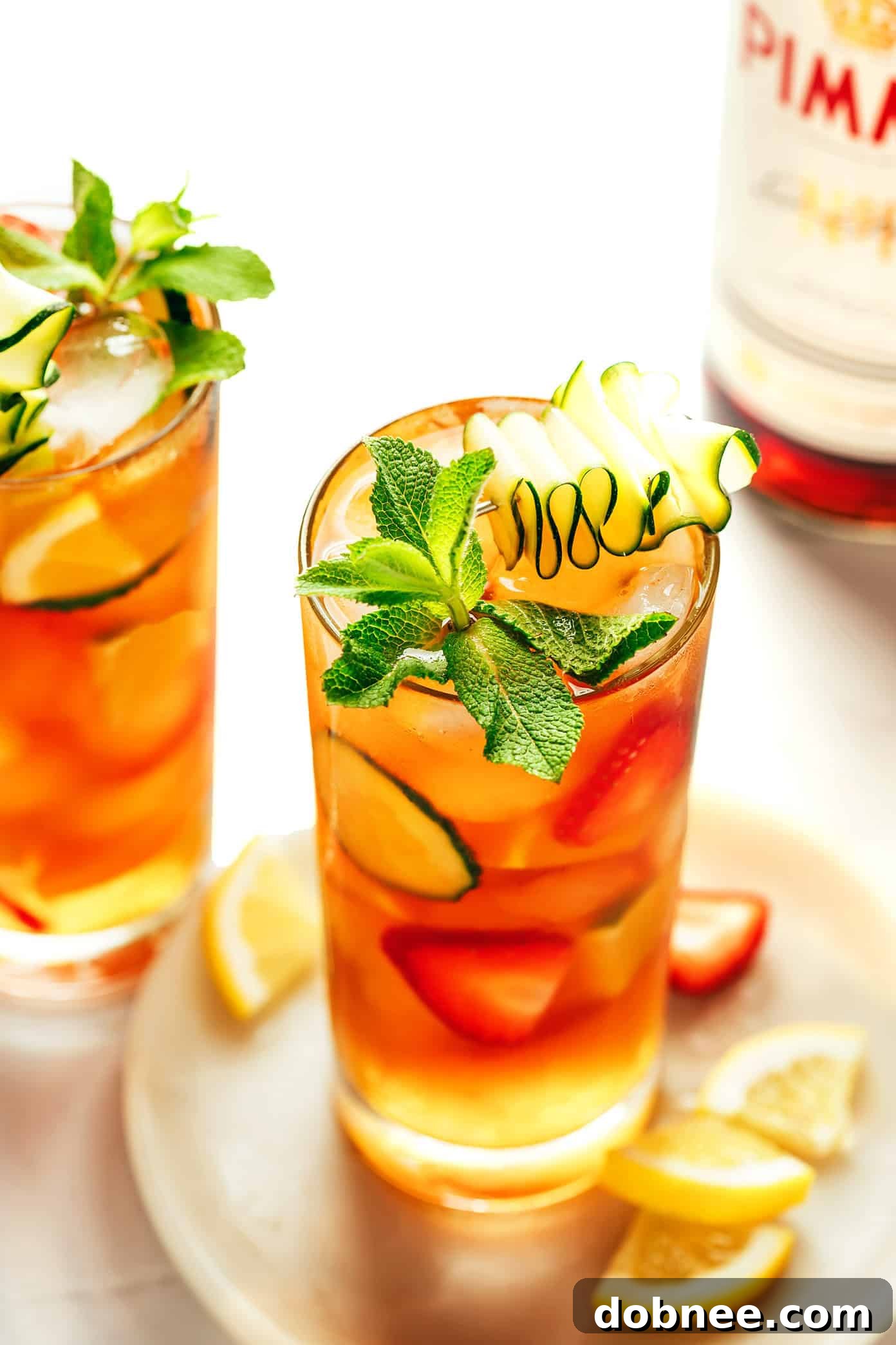 A refreshing Pimm's Cup cocktail garnished with fresh fruit and mint, perfect for summer.