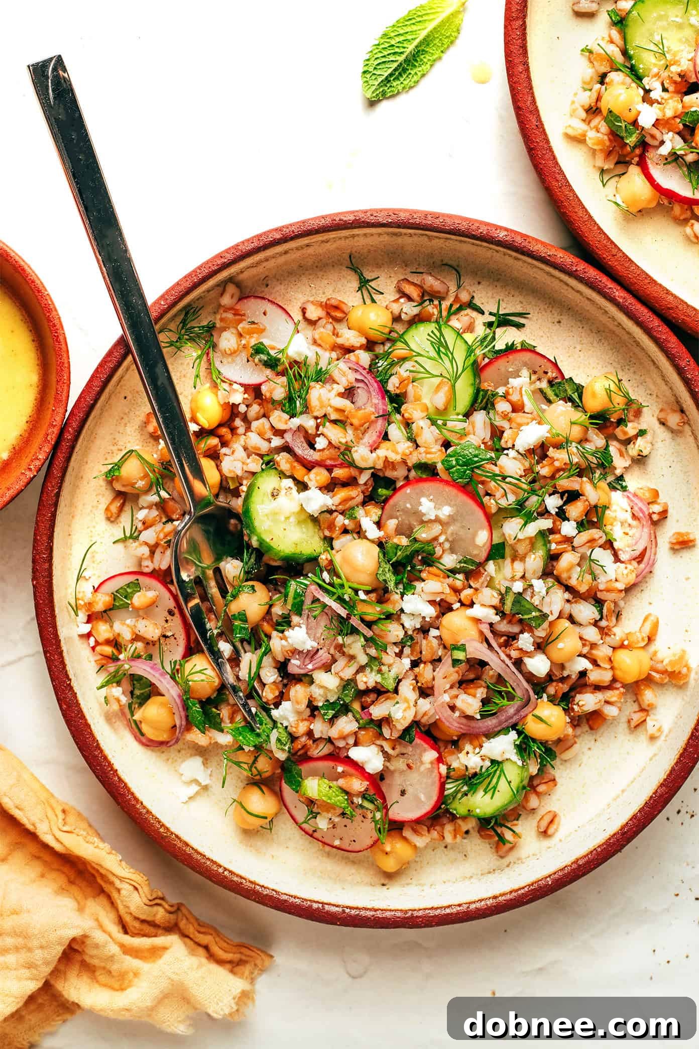 Bright and colorful spring farro salad with fresh vegetables and herbs, served in a bowl.