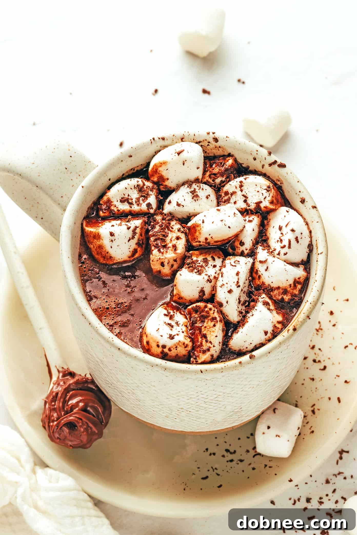 A vibrant mug of Nutella Hot Chocolate with a generous topping of whipped cream and chocolate shavings.