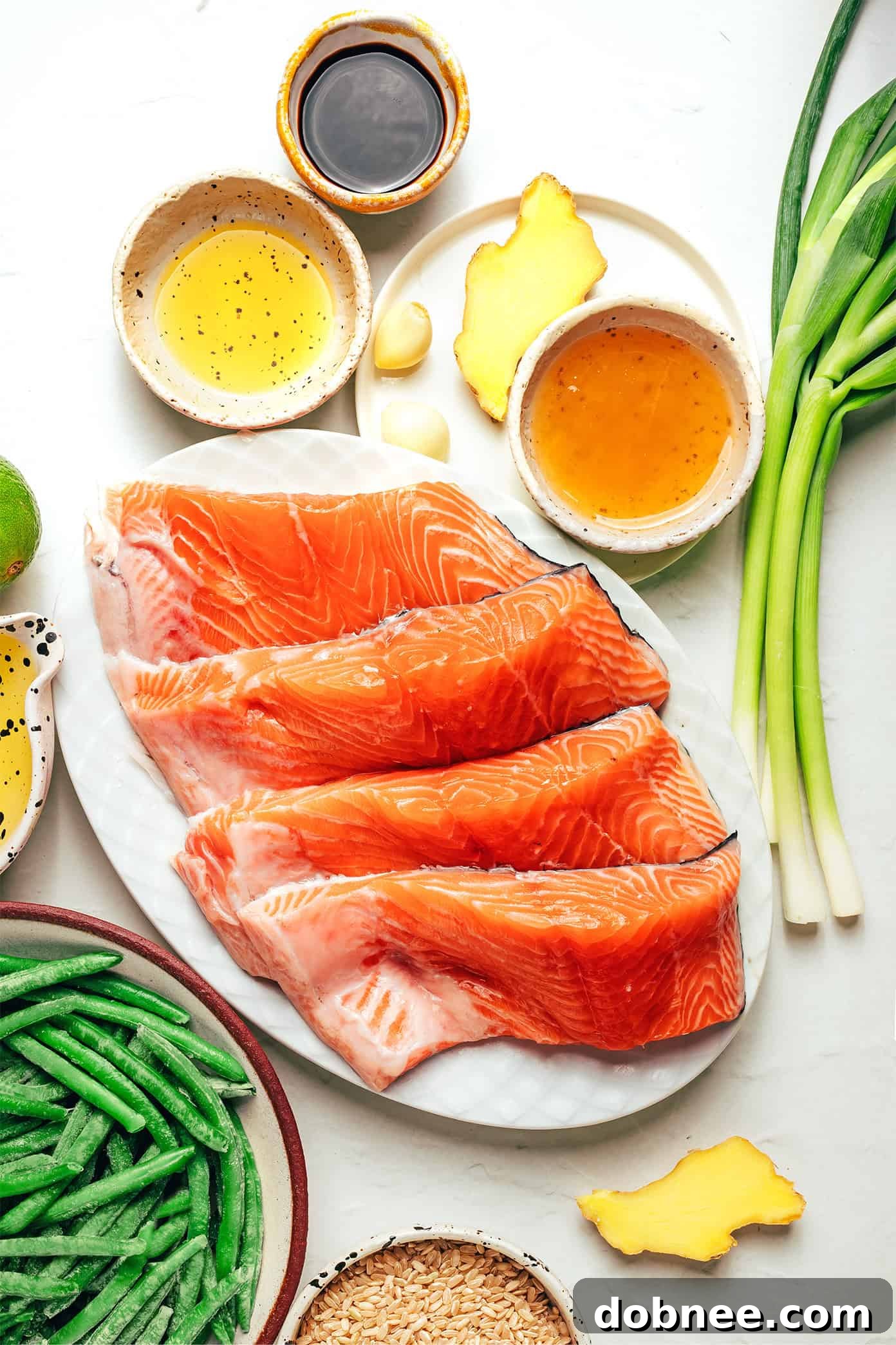 Close-up of a honey-roasted salmon fillet on a plate, garnished with fresh lime and scallions.