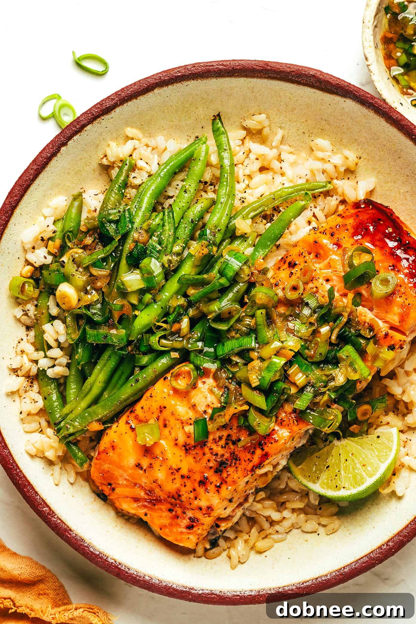 A final serving of honey-roasted salmon with green beans and rice, drizzled with sauce and a lime wedge.