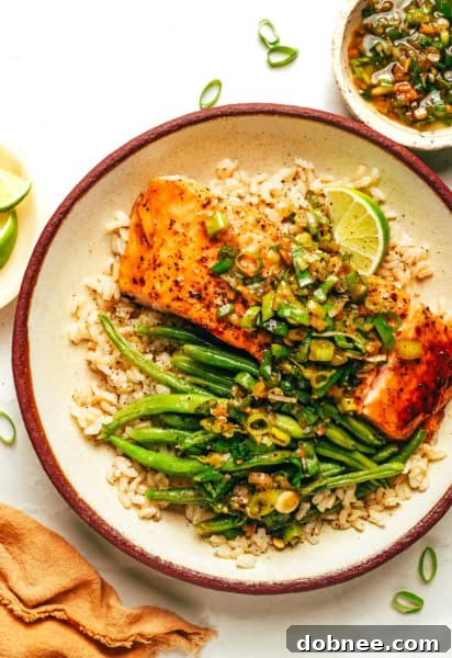 Honey Salmon with Ginger Scallion Sauce served with green beans and rice, garnished with fresh lime.