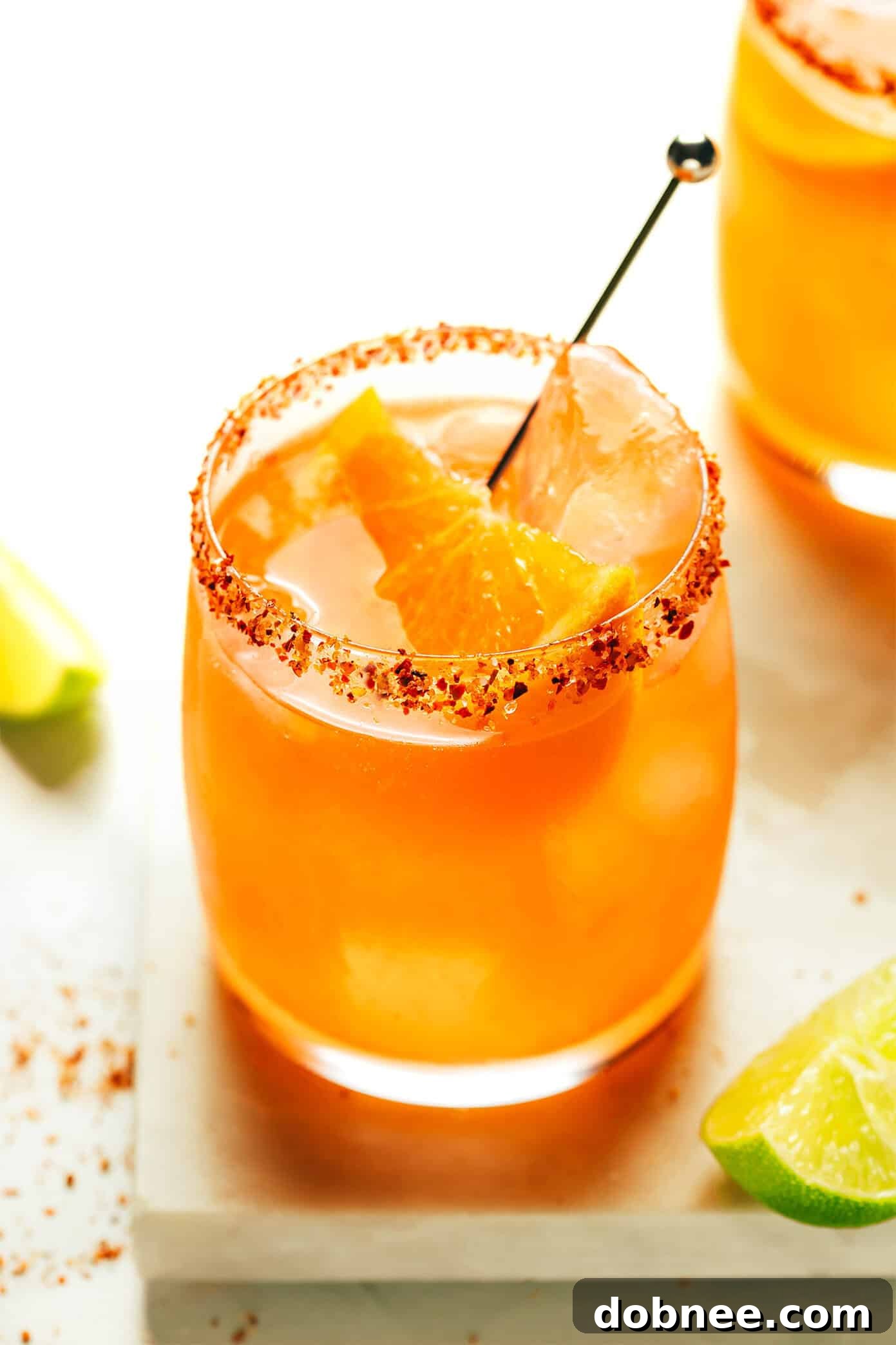 A vibrant Aperol Margarita garnished with an orange slice, resting on a coaster.