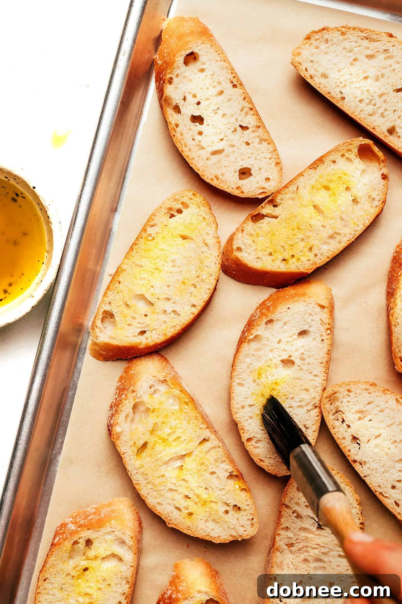 Three golden-brown crostini slices, drizzled with olive oil and sprinkled with flaky sea salt, on a white surface.