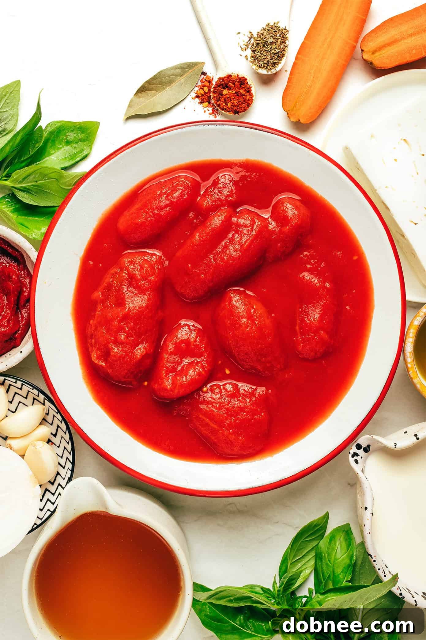 Two bowls of tomato feta soup, one in the foreground, showing the creamy texture and feta pieces. Fresh basil leaves are visible as garnish.