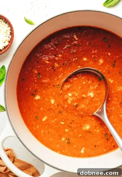 A vibrant bowl of homemade tomato feta soup, garnished with fresh basil leaves and crumbled feta cheese, ready to be served.