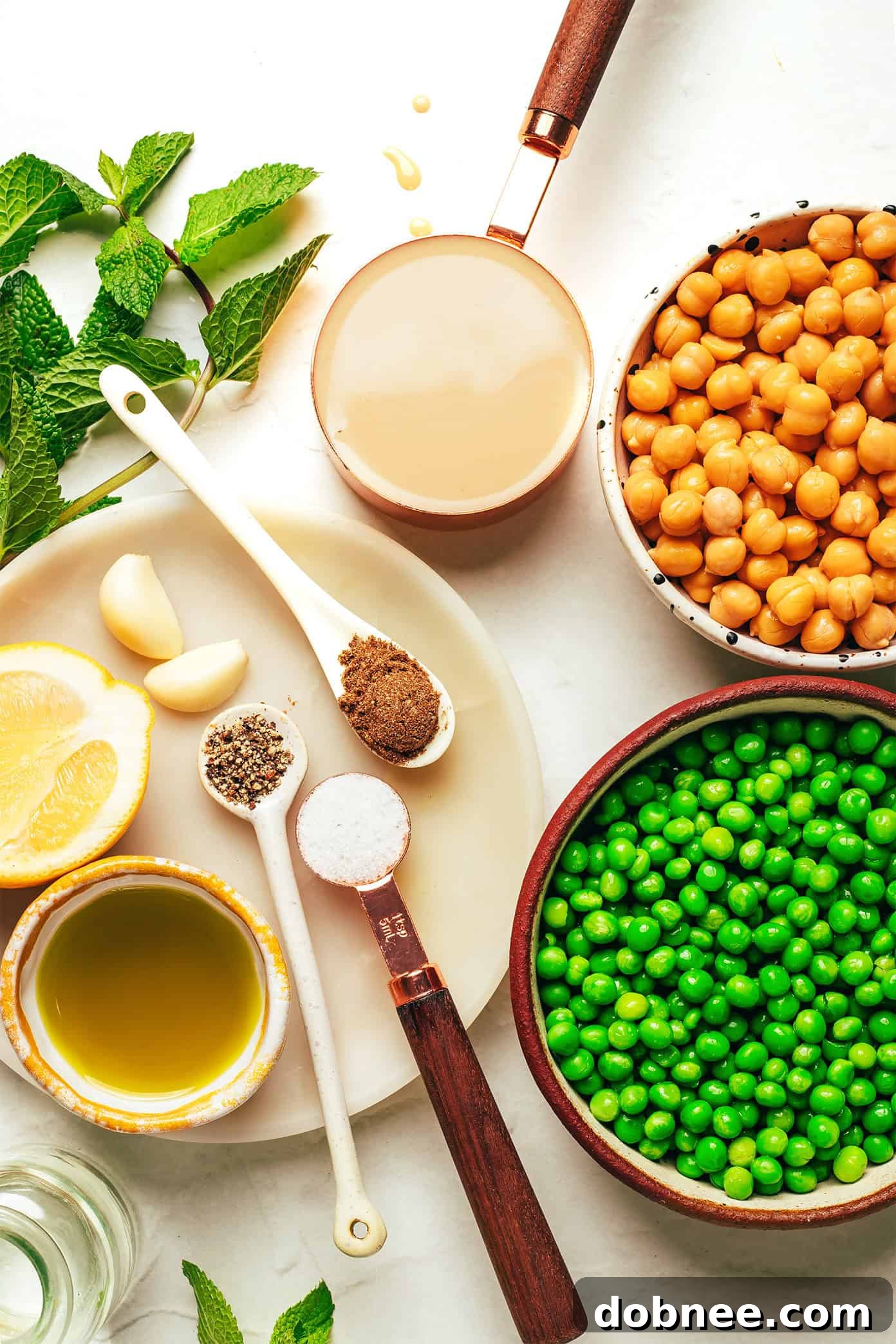 Vibrant Mint & Pea Hummus 3 A bowl of vibrant green mint pea hummus, seen from a different angle, highlighting its smooth, creamy texture. Garnished lightly with olive oil and a few whole chickpeas.