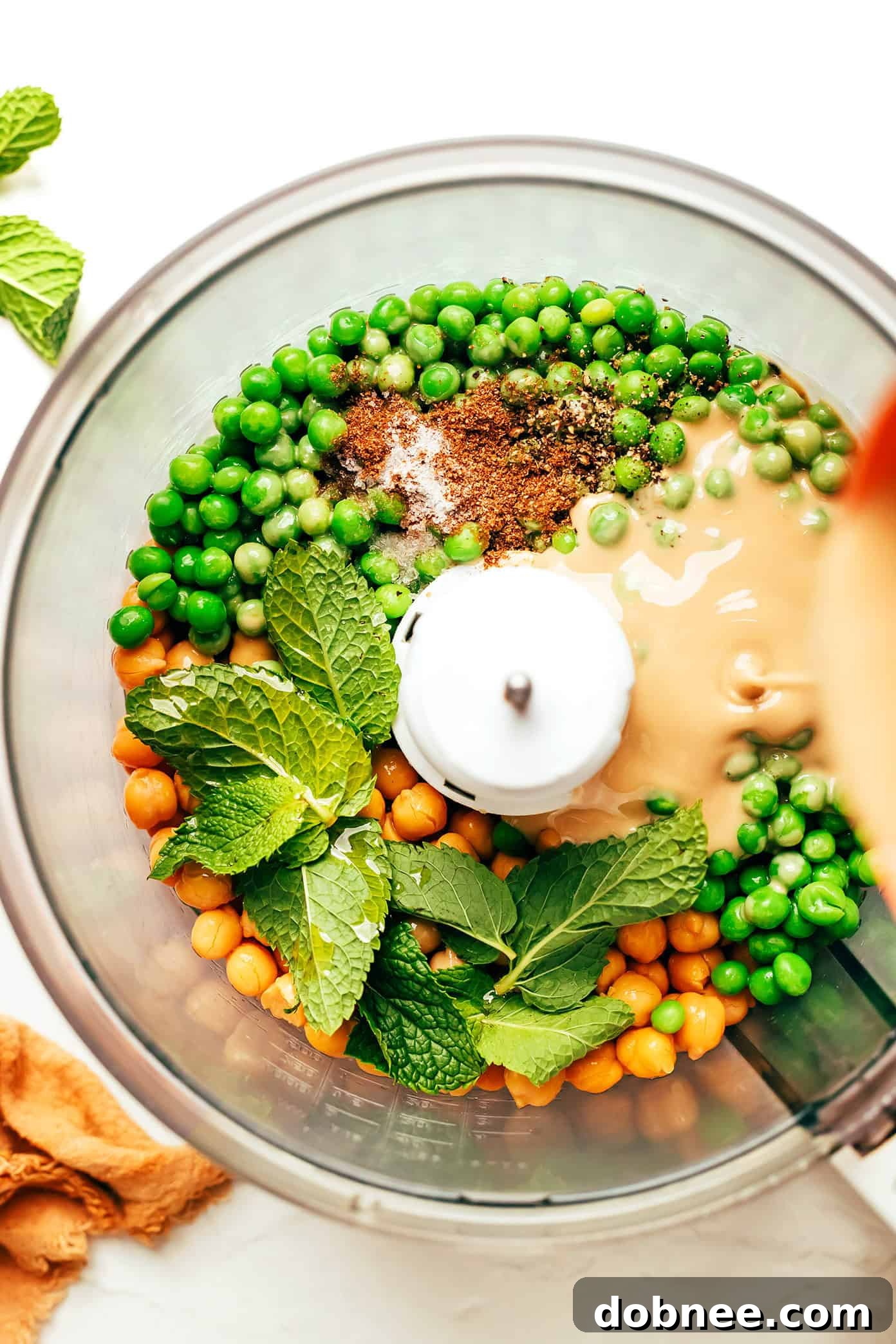 Vibrant Mint & Pea Hummus 4 Close-up of the smooth, creamy texture of mint pea hummus, showing a swirl in the middle, garnished with olive oil.