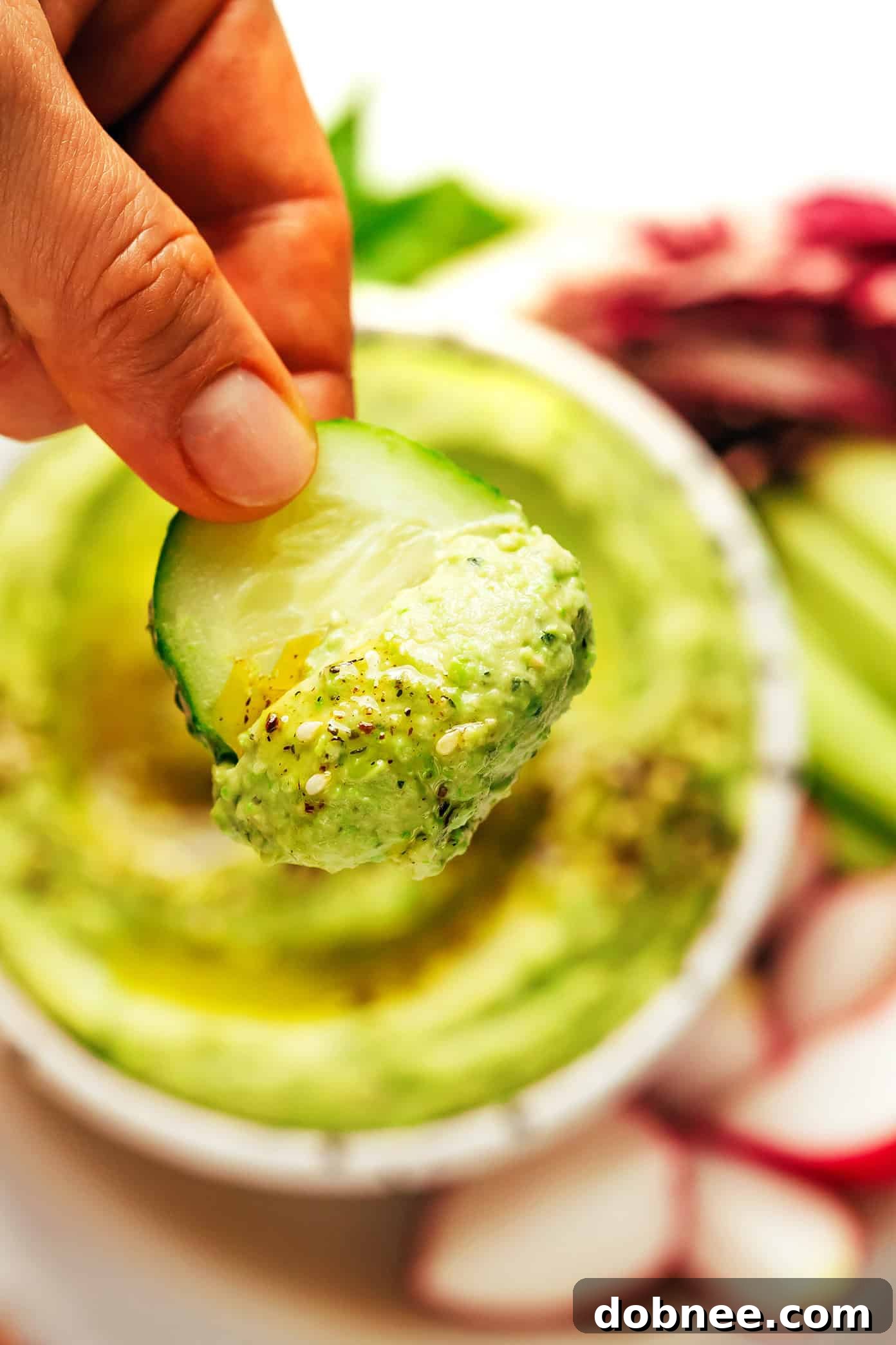 Vibrant Mint & Pea Hummus 6 A bowl of mint pea hummus on a wooden surface, garnished with fresh mint, a drizzle of olive oil, and served with an assortment of dippers like pita bread, cucumber slices, and carrot sticks.