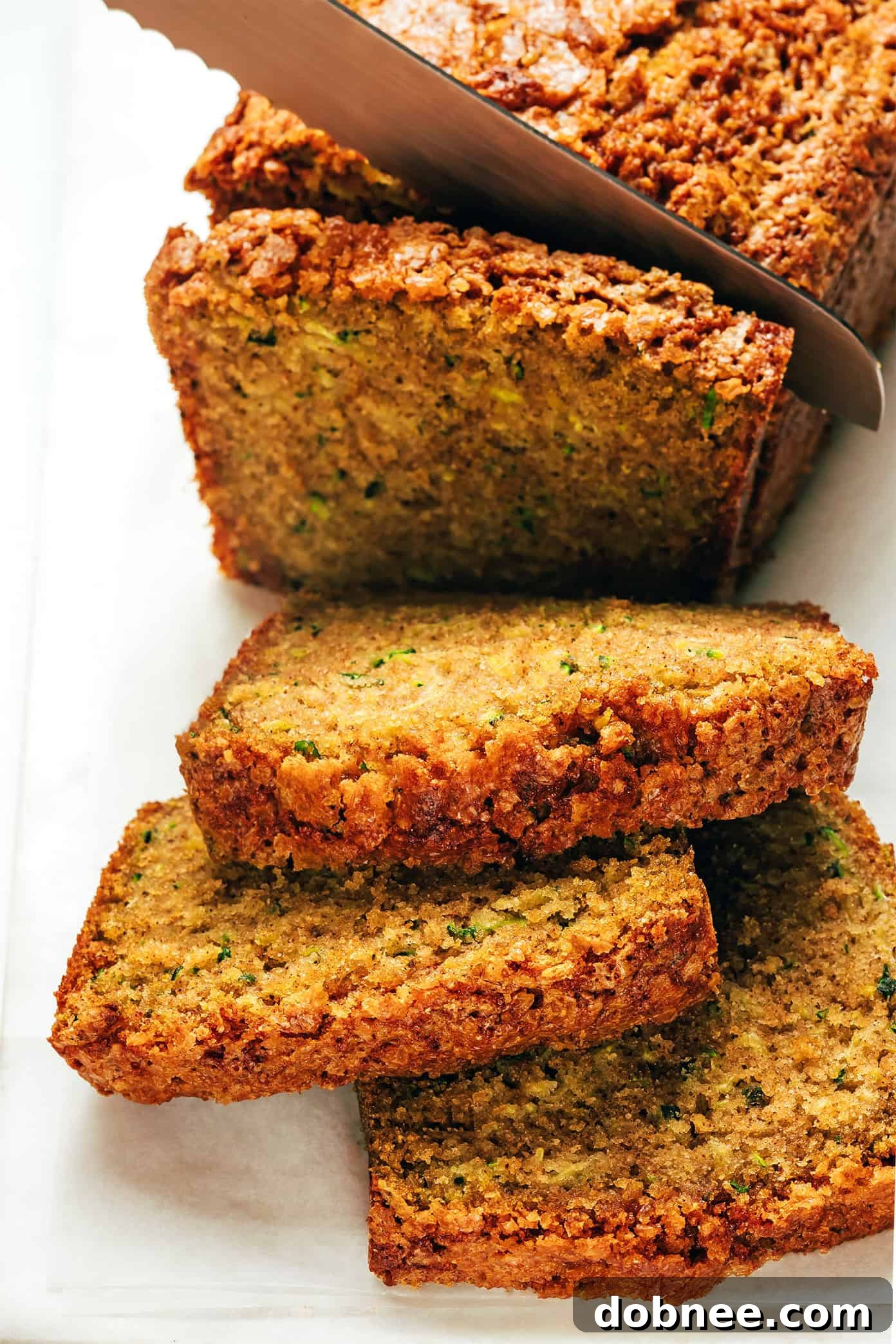 Freshly baked zucchini bread loaf with a crunchy sugar topping, sliced and ready to serve.
