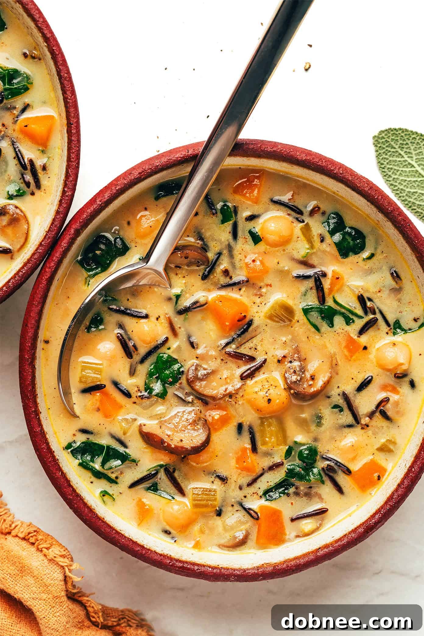 Delicious and creamy pumpkin wild rice soup in a bowl, garnished with fresh sage leaves, perfect for fall.