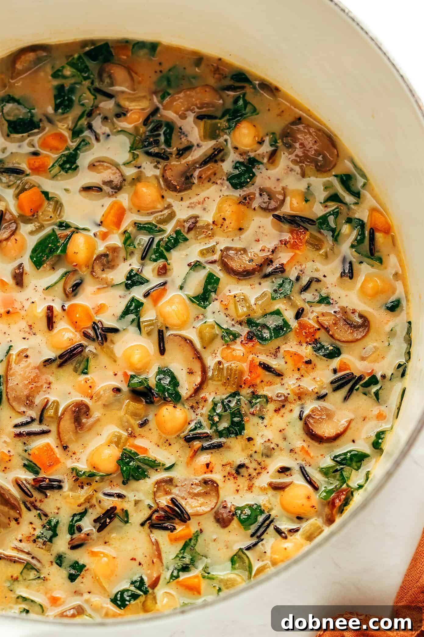 A bowl of pumpkin wild rice soup on a rustic wooden table with a spoon, highlighting its inviting warmth.