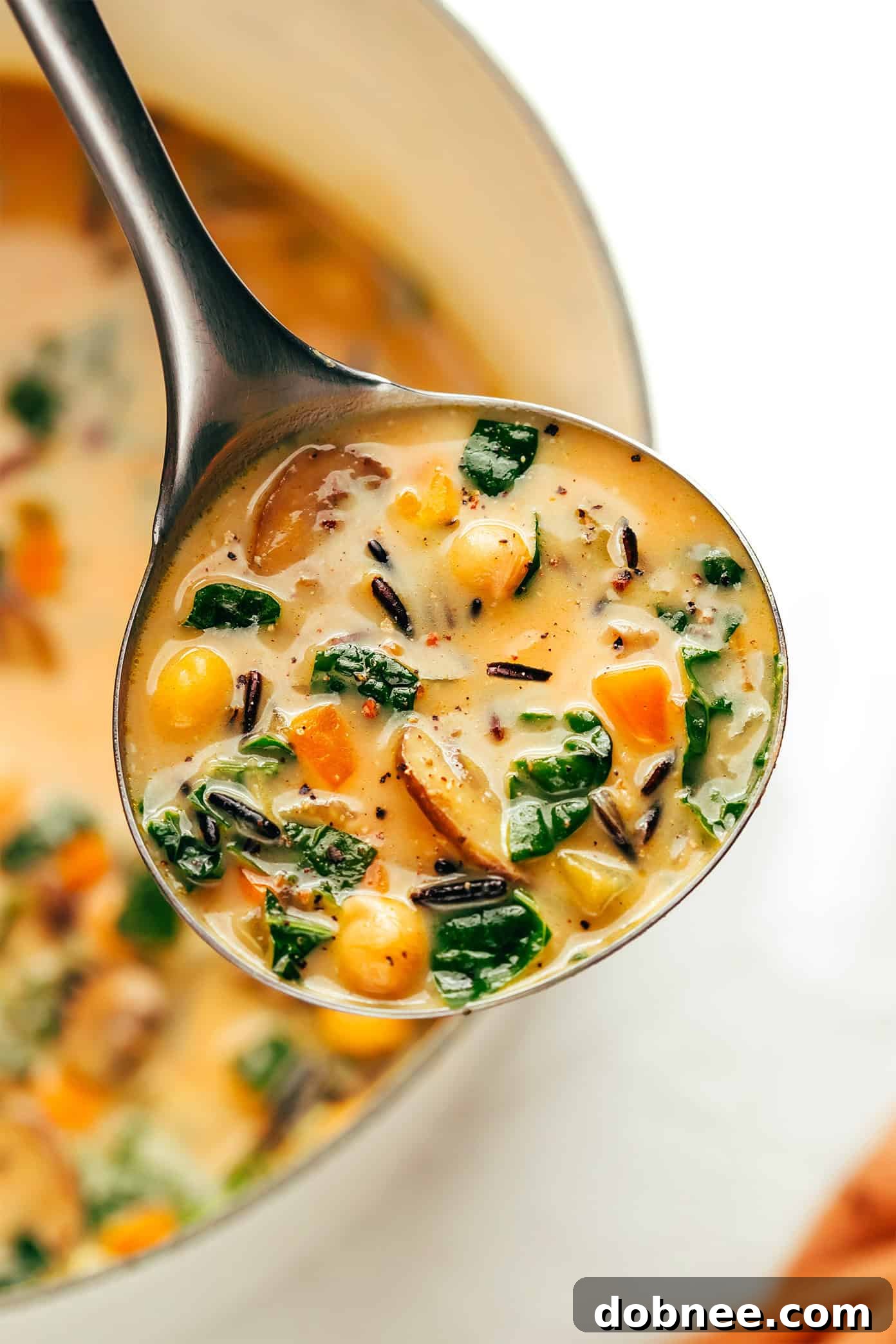 Six bowls of pumpkin wild rice soup arranged on a wooden table, ready to be served.