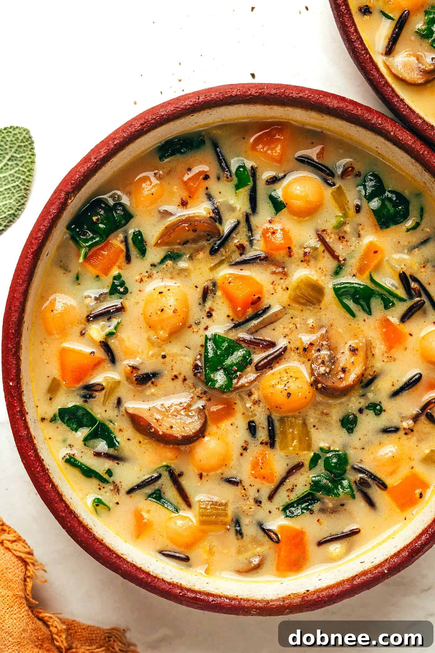 A close-up of a single bowl of pumpkin wild rice soup, showing the vibrant colors and hearty ingredients.